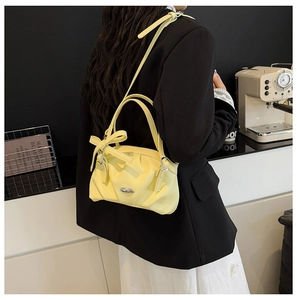 Détail du sac en cuir jaune clair avec nœud décoratif et boucles métalliques argentées