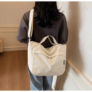 Detail view of large cream tote bag showing texture and logo with model perspective