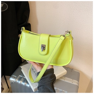 Close-up of neon green shoulder bag with silver push-lock and glossy leather texture