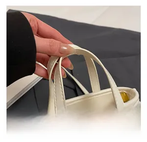 Detail of soft cream leather handbag handles with gold hardware and woven rope decor