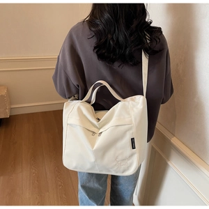Close-up of a white canvas tote bag with detailed animal embroidery and adjustable strap