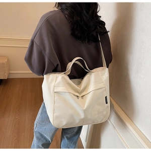 Close-up of ivory tote bag featuring branded logo embossing and durable nylon texture