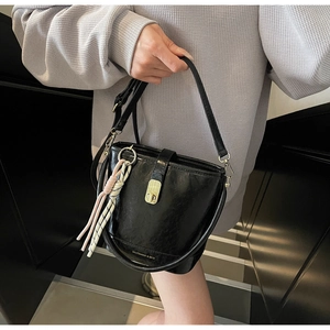 Détail du sac seau en cuir noir brillant avec fermoir doré et ruban de soie rayé