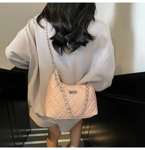 Close-up of pink quilted crossbody bag featuring silver turn-lock and chain strap