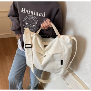 Detail of cream white tote bag featuring cute bear embroidery and woven brand label