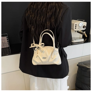 Détail du sac à main plissé blanc cassé avec poignée à nœud et accent métallique sur modèle