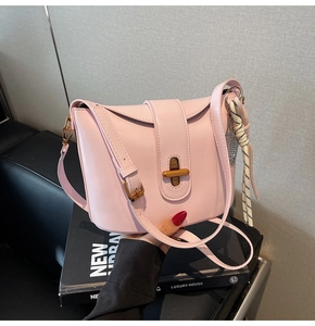Pink minimalist crossbody bucket bag with golden twist lock and decorative scarf detail