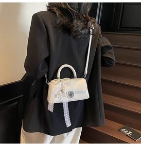 Detail of pearl white crossbody bag with lace bow, pearl chain and silver heart charm