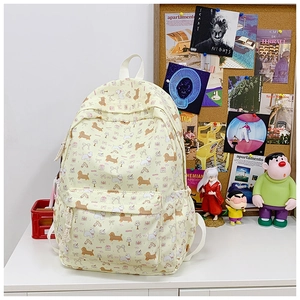 Detail view of beige canvas backpack featuring cute cartoon dog prints and front pocket