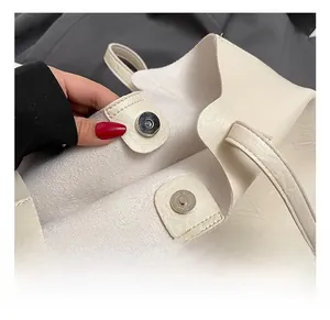 Close-up of a silver magnetic snap closure on a beige faux leather tote bag