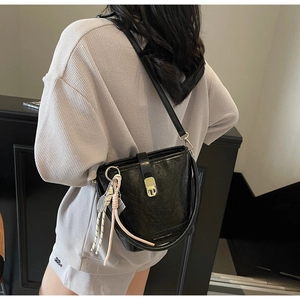 Détail du sac seau en cuir noir avec boucle dorée et breloque raquette de tennis