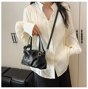 Détail du sac à main en cuir grainé noir avec design froncé et garnitures argentées