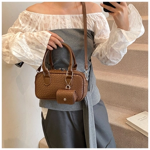 Detail of a brown woven texture Boston bag featuring a matching mini coin purse charm