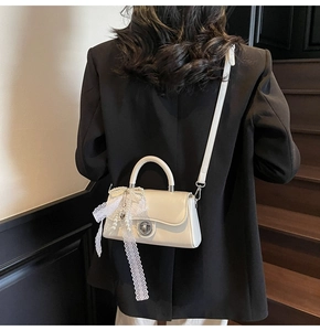 Detail of cream mini crossbody bag with lace bow, pearl chain and metal twist lock