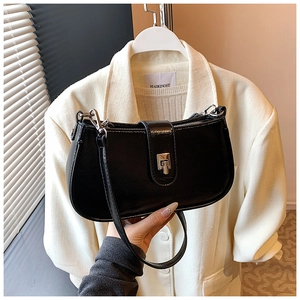Detail of black glossy leather shoulder bag with silver metal buckle and zipper