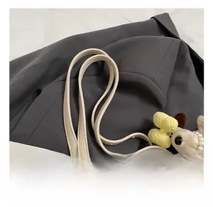 Detail of adjustable slim shoulder strap with silver buckle on cream tote bag