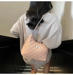 Side view of pink quilted crossbody bag with metal chain strap and turn-lock closure