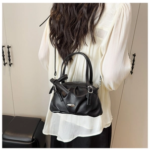 Détail d'un sac à main noir en cuir grainé avec un nœud et un fermoir en métal argenté