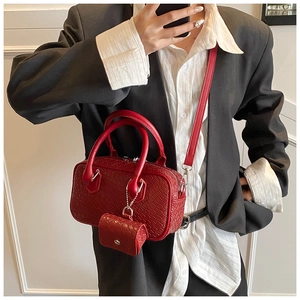 Detail of red woven handbag featuring a matching mini zip pouch and textured vegan leather
