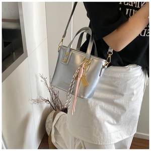 Detail of silver metallic tote bag with gold hardware and brand logo on model