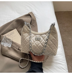 Detailed view of cream quilted crossbody bag with silver chain and metal turn-lock closure