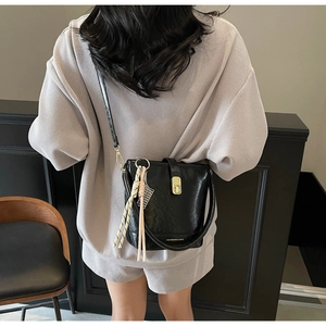 Détail du sac seau noir avec texture plissée brillante et breloque en foulard de soie