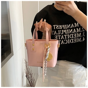 Detailed close-up of pink bucket bag with gold hardware and stylish striped scarf accessory