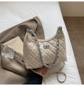 Close-up of beige quilted hobo bag with silver chunky chain and metal twist lock detail