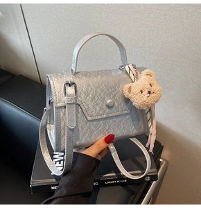 Detailed view of silver textured leather mini square bag with a cute plush bear charm