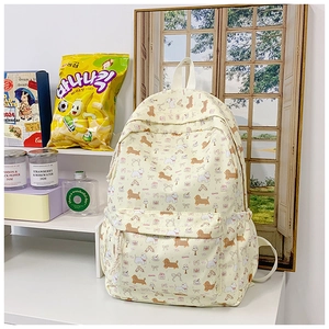 Detail view of cream backpack featuring all-over cartoon puppy print and front pocket