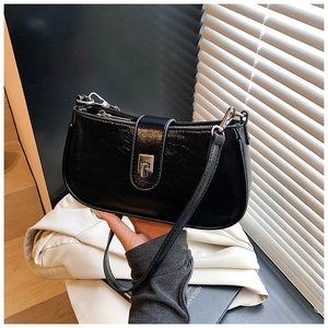 Detail of black glossy oil wax leather hobo bag with sleek silver buckle and fine texture