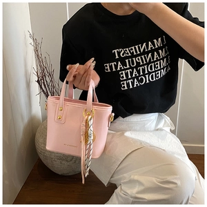 Close-up of pink leather bucket bag with golden hardware and striped scarf detail