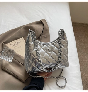 Close-up of silver quilted crossbody bag with chunky metal chain and turn-lock closure