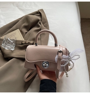 Detail of pink crossbody bag with silver ring lock and pearl lace bow accessory