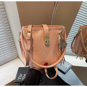 Détail d'un sac seau en cuir rose clair avec fermoir doré et logo embossé avec soin