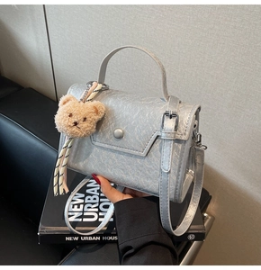 Detail of silver textured mini square bag with plush bear charm and adjustable strap