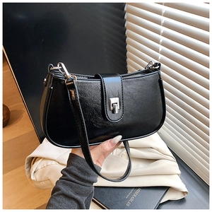 Detail of black glossy leather shoulder bag featuring silver square buckle and crinkled texture