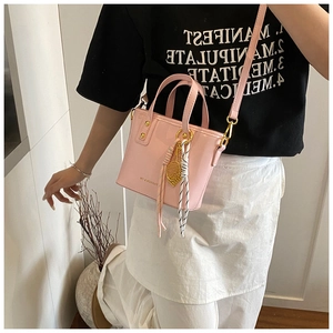 Detail showing light pink PU leather tote bag with tennis racket charm and removable strap