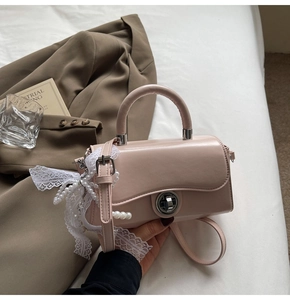 Detail of pink leather handbag with white lace ribbon and pearl chain accessory