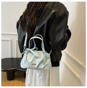 Détail du sac plissé bleu clair avec décoration de nœud et boucle en métal argenté