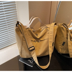 Macro view of khaki nylon tote bag showing dual zipper pockets and fabric logo label