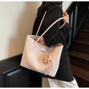 Dettaglio della borsa tote rosa con trama intrecciata e ciondolo a forma di orsetto