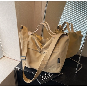 Detail of beige canvas tote bag featuring dog embroidery and adjustable black strap