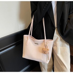 Dettaglio borsa shopper rosa con trama diagonale, logo in metallo e charm a orsetto