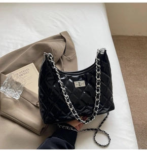Close-up of black quilted patent leather bag with silver chain strap and metal lock