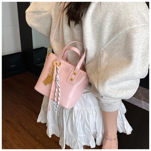 Detailed view of pink mini tote bag featuring silk scarf knots and golden charms