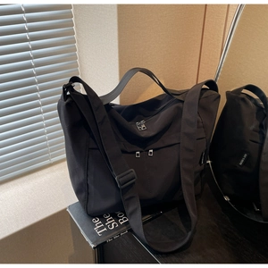 Detail of black nylon tote bag with dual front zippers and YOU BEAR side woven label