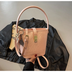 Détail du sac seau rose avec fermoir doré rotatif et texture de cuir élégante