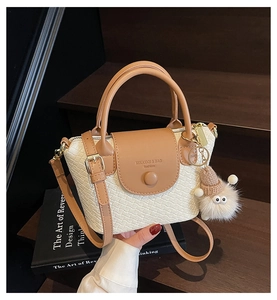 Détail du sac seau tissé avec bordure en cuir marron et breloque pompon en peluche blanche