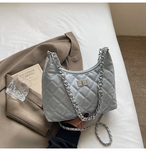 Close-up of light grey-blue quilted hobo bag with silver metal chain and twist lock